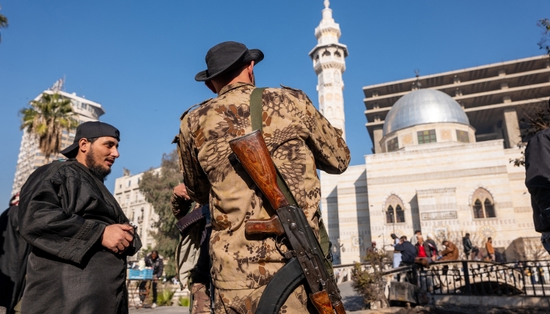 Members of the insurgent group Hayat Tahrir al-Sham, or HTS, stand in a square on 19 January 2025 in Damascus, Syria.