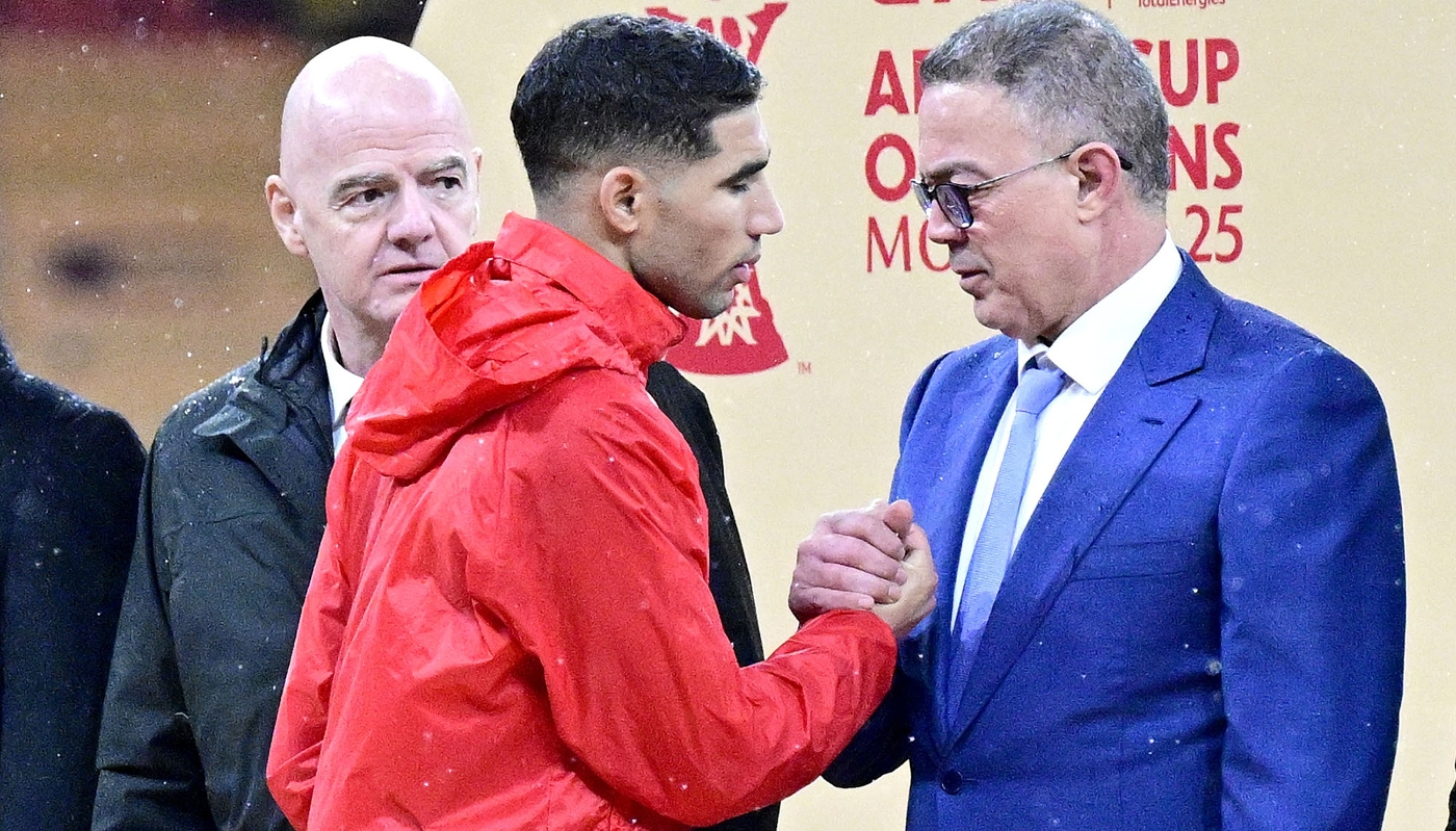 Fouzi Lekjaâ (right) shakes hands with Moroccan team captain Achraf Hakimi, as FIFA President Giovanni Infantino looks on, 18 January 2026.