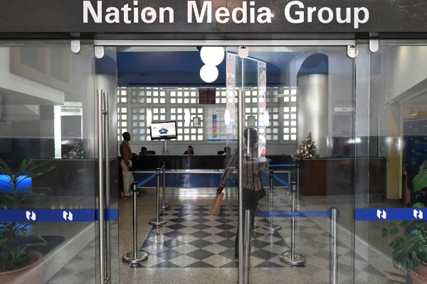 People walk at the entrance to the headquarters of Kenyan 'Nation Media Group' (NMG) in Nairobi on 19 January 2018.