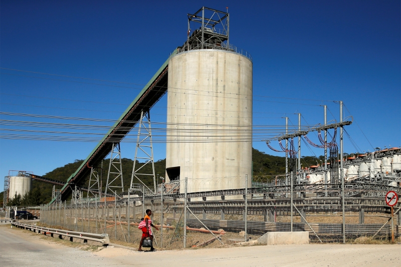 A woman walks past Anglo American Platinum's Unki mine in Shurugwi, Zimbabwe.